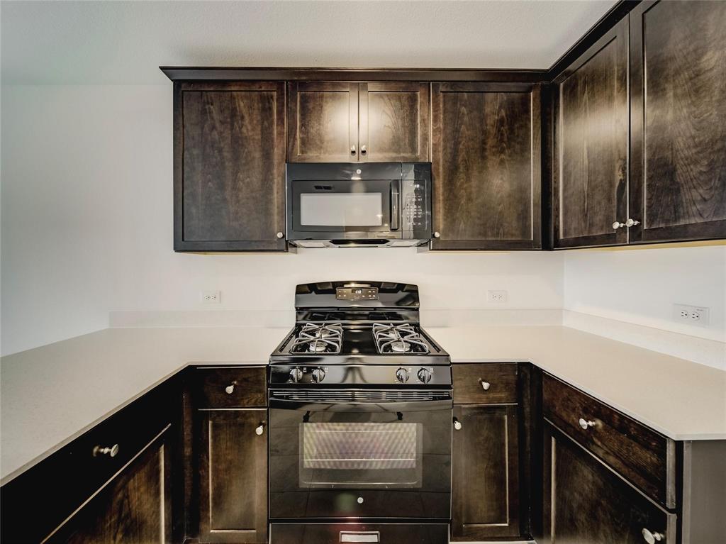 357 Sun Bluff Road Fort Worth, TX 76052 - Photo 6 of 35 Kitchen featuring dark wood cabinetry, light-toned countertops, a black gas range, and an over-the-range microwave