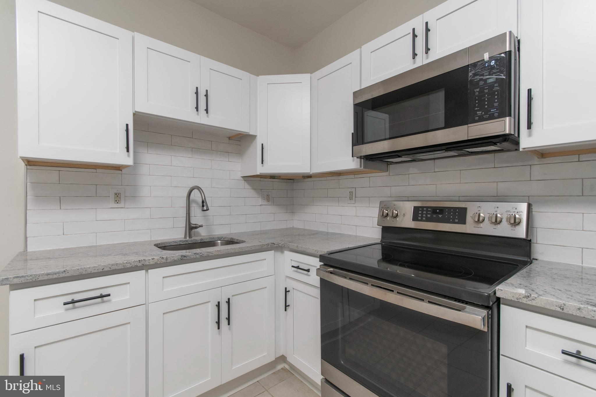 725 West Luzerne Street Philadelphia, PA 19140 - Photo 7 of 23 a kitchen with granite countertop white cabinets and a stove top oven