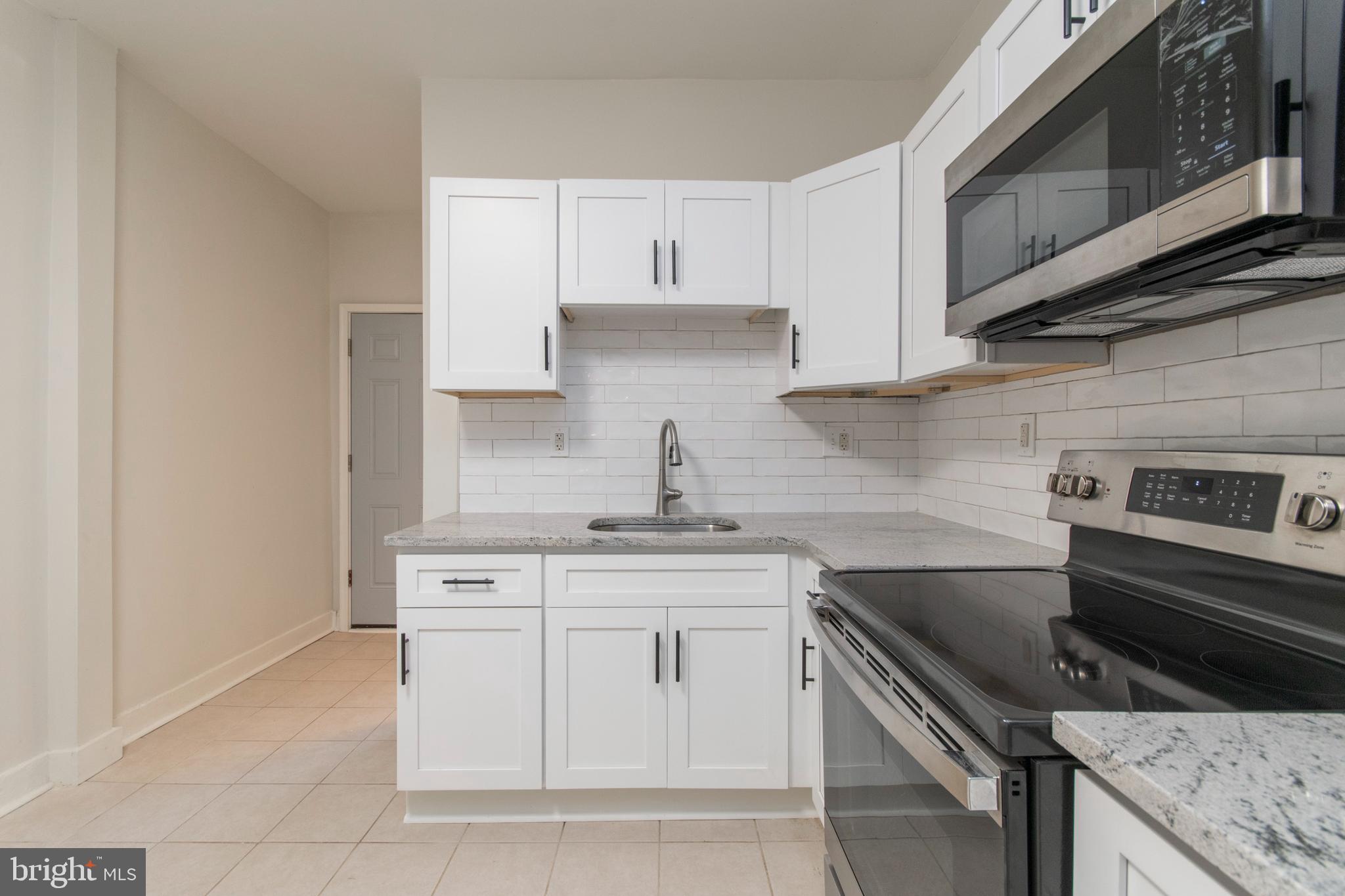 725 West Luzerne Street Philadelphia, PA 19140 - Photo 8 of 23 a kitchen with white cabinets stainless steel appliances and sink