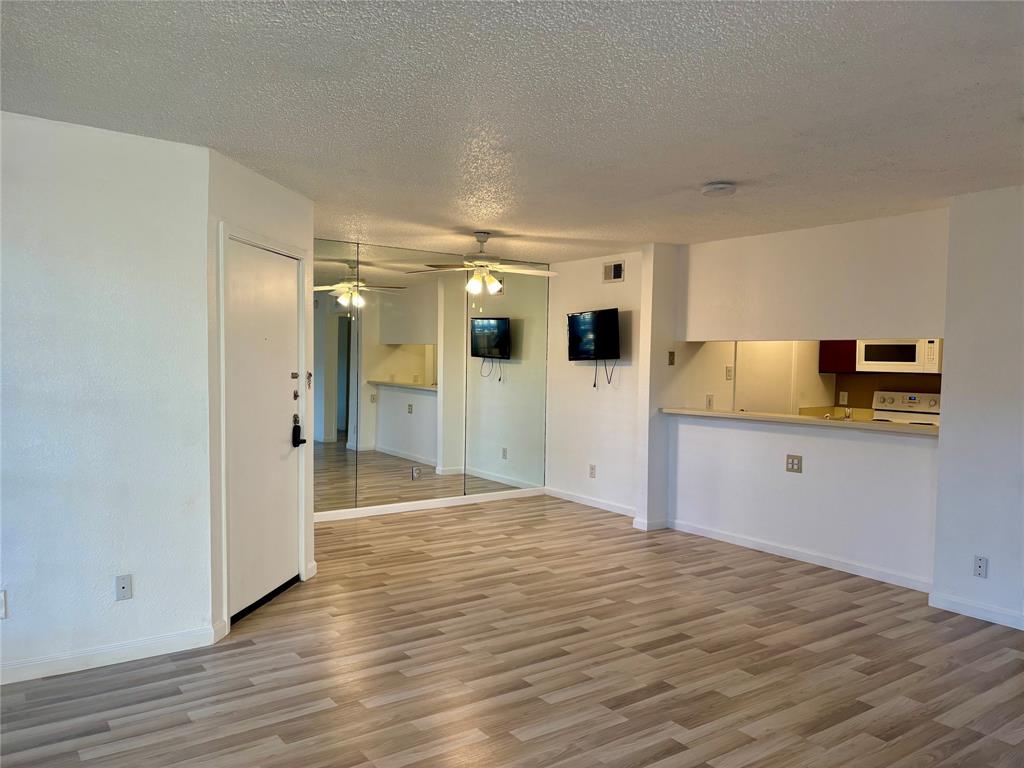 12480 Abrams Road, Unit 2805 Dallas, TX 75243 - Photo 5 of 18 Unfurnished living room with light wood-type flooring, a textured ceiling, and ceiling fan