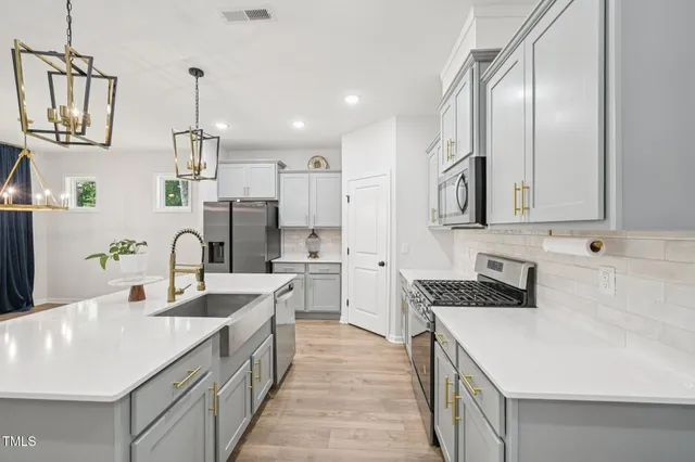 a view of a kitchen with wooden floor electronic appliances and windows