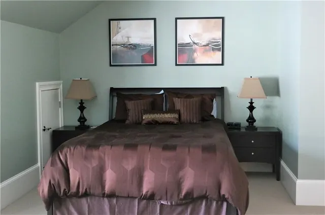 a bedroom with a bed and a lamp on dresser