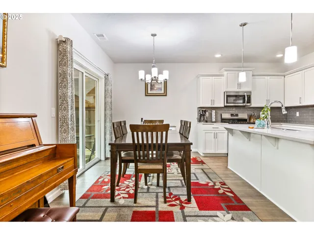 a open kitchen with stainless steel appliances kitchen island granite countertop a dining table chairs and granite counter tops