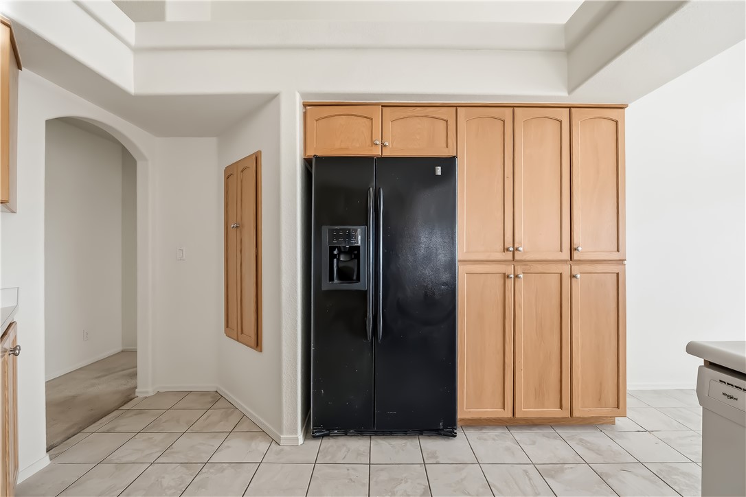 2853 Winchester Road Bullhead City, AZ 86442 - Photo 17 of 40 Kitchen area featuring a black side-by-side refrigerator, extensive light wood-finish cabinetry, and neutral-toned tile flooring