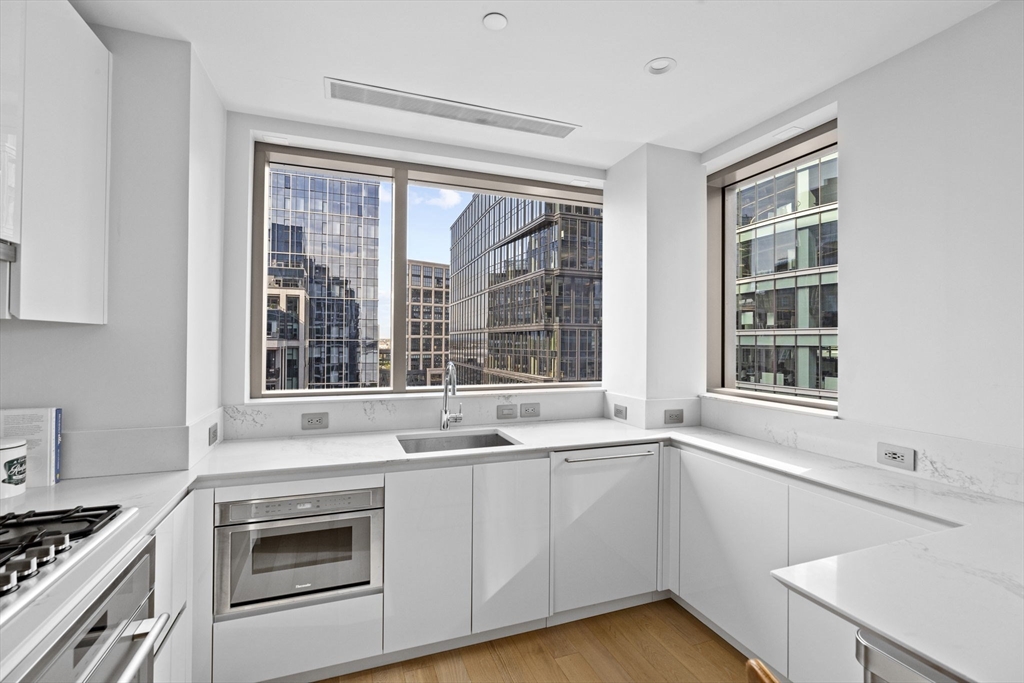 133 Seaport Boulevard, Unit 1603 Boston, MA 02210 - Photo 6 of 32 a kitchen with a sink stove and cabinets
