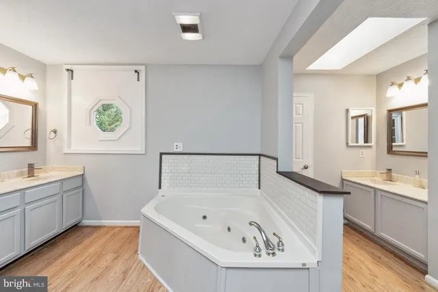 a spacious bathroom with a tub sink and mirror