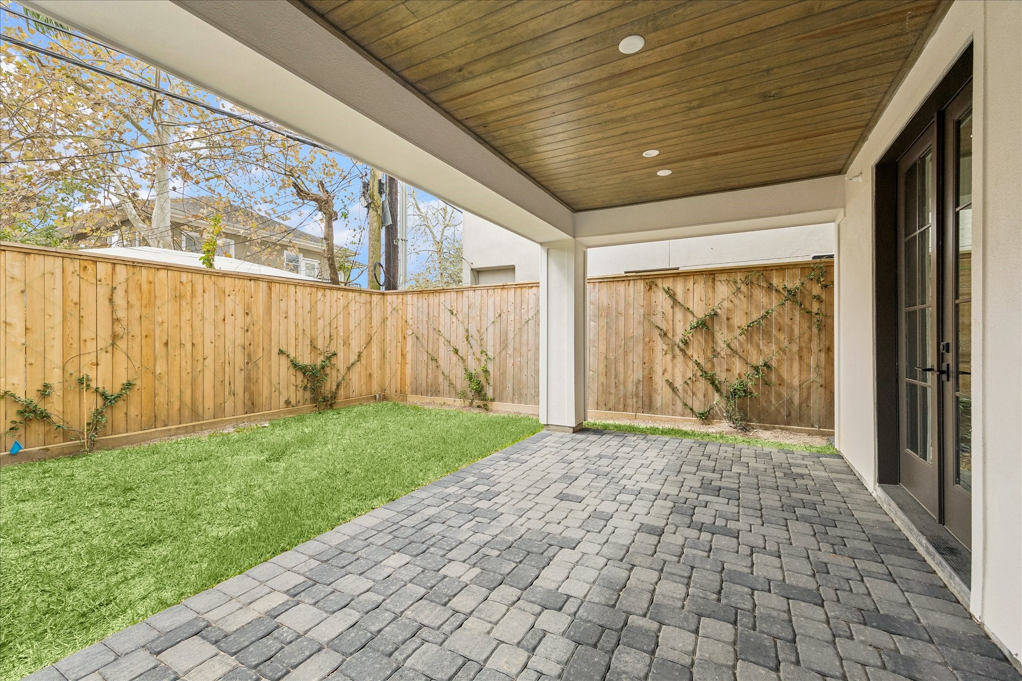 1215 West Pierce Street Houston, TX 77019 - Photo 36 of 37 The first-floor Pavilion features a wood-plank ceiling with recessed lighting, cobblestone pavers, and lush lawn—a private outdoor retreat enclosed by cedar fencing with climbing vines. French doors connect seamlessly to the first-floor bedroom, whether used as a guest suite, office, or gym.