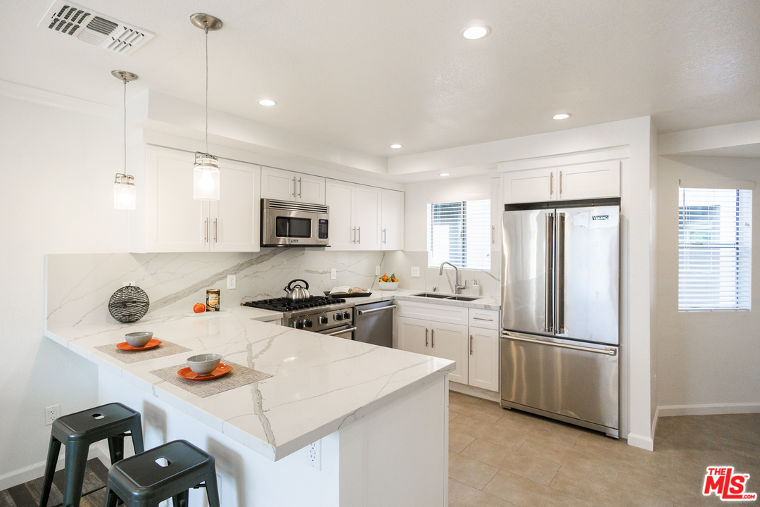 1085 West Kensington Road Los Angeles, CA 90026 - Photo 5 of 23 a kitchen with stainless steel appliances a stove a sink dishwasher a refrigerator and a refrigerator with wooden floor