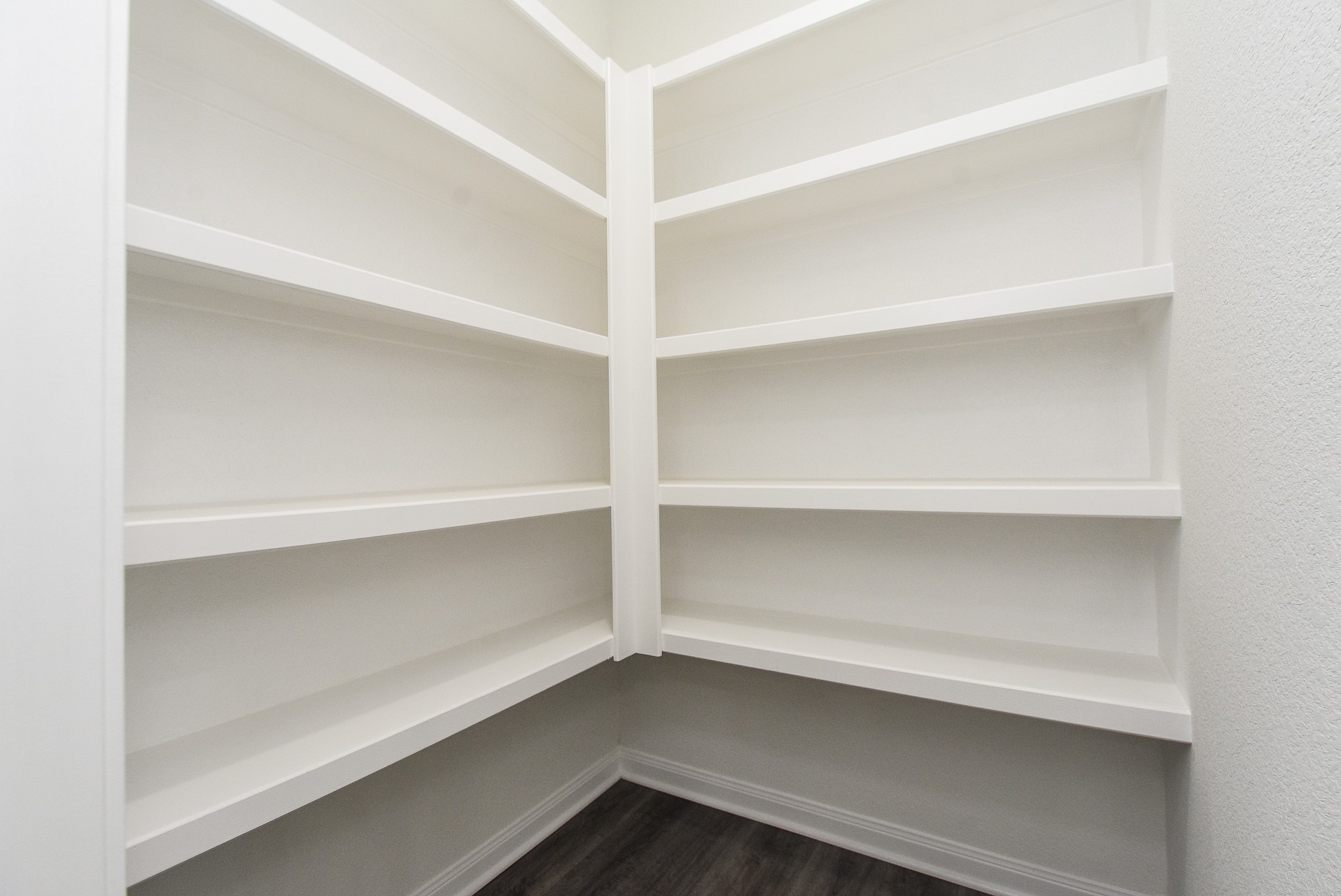2811 Topiary Lane Houston, TX 77014 - Photo 24 of 32 An empty corner closet with white shelves and grey flooring in a clean, modern interior.