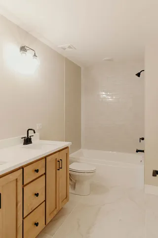 a bathroom with a granite countertop sink a toilet and shower