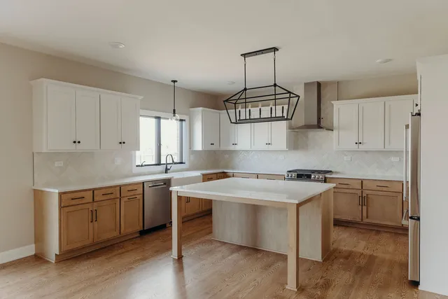 a kitchen with stainless steel appliances a sink a stove a refrigerator and white cabinets