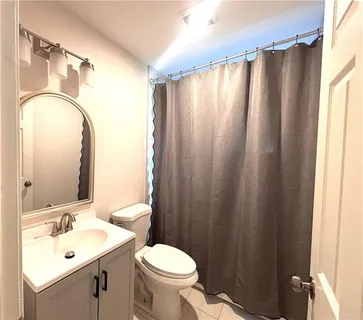 a bathroom with a sink a toilet a mirror and shower curtain