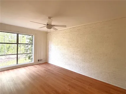 an empty room with wooden floor and windows with curtains