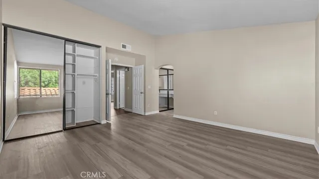 an empty room with wooden floor mirror and windows