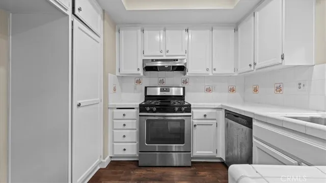 a kitchen with cabinets appliances and wooden floor