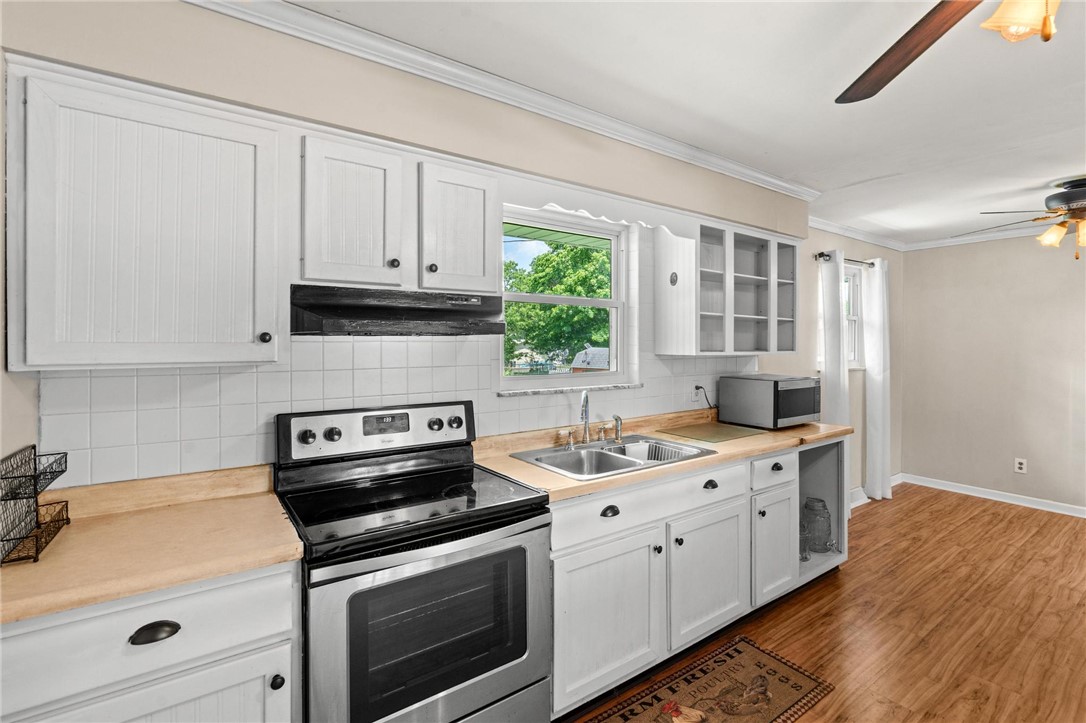 4150 Rose Marie Road Franklin, OH 45005 - Photo 24 of 36 A classic kitchen setup features white cabinetry, wood flooring, and a window overlooking a verdant outdoor space.