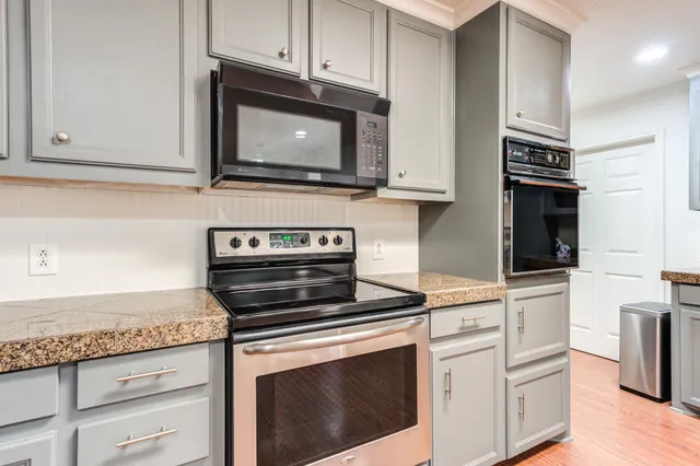 a large kitchen with granite countertop a sink and dishwasher stove top oven with wooden floor