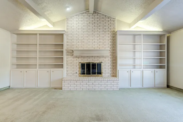 a view of an empty room with a fireplace and cabinets