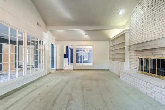 a view of an empty room with a fireplace and a window