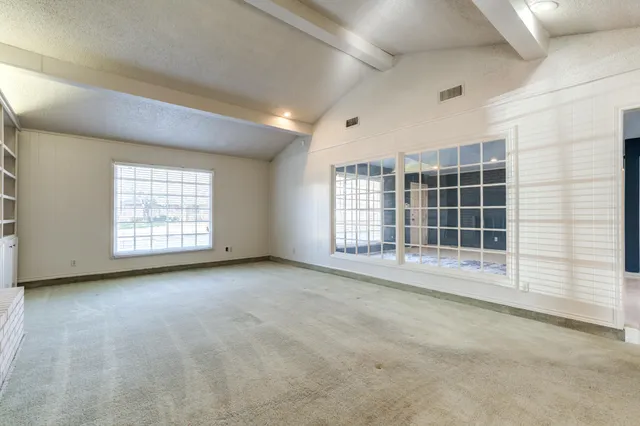a view of an empty room with a window and cabinet