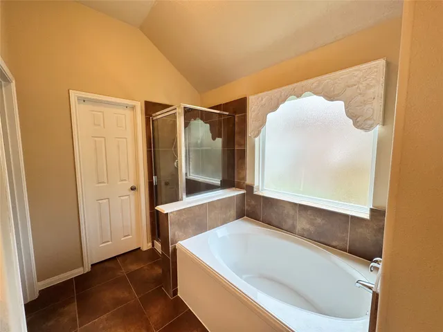 a spacious bedroom with a bed a mirror on dresser and a chandelier