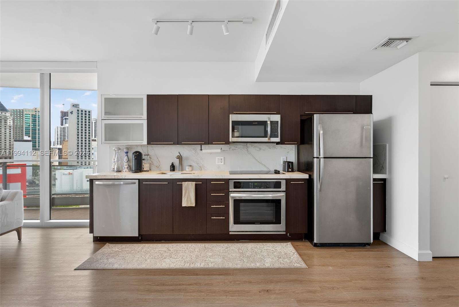 90 Southwest 3rd Street, Unit 1105 Miami, FL 33130 - Photo 7 of 11 a kitchen with a refrigerator stove and wooden floor