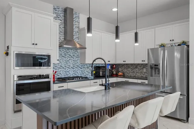 a kitchen with stainless steel appliances granite countertop a sink a stove and a refrigerator