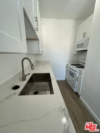 a kitchen with granite countertop white cabinets and white appliances