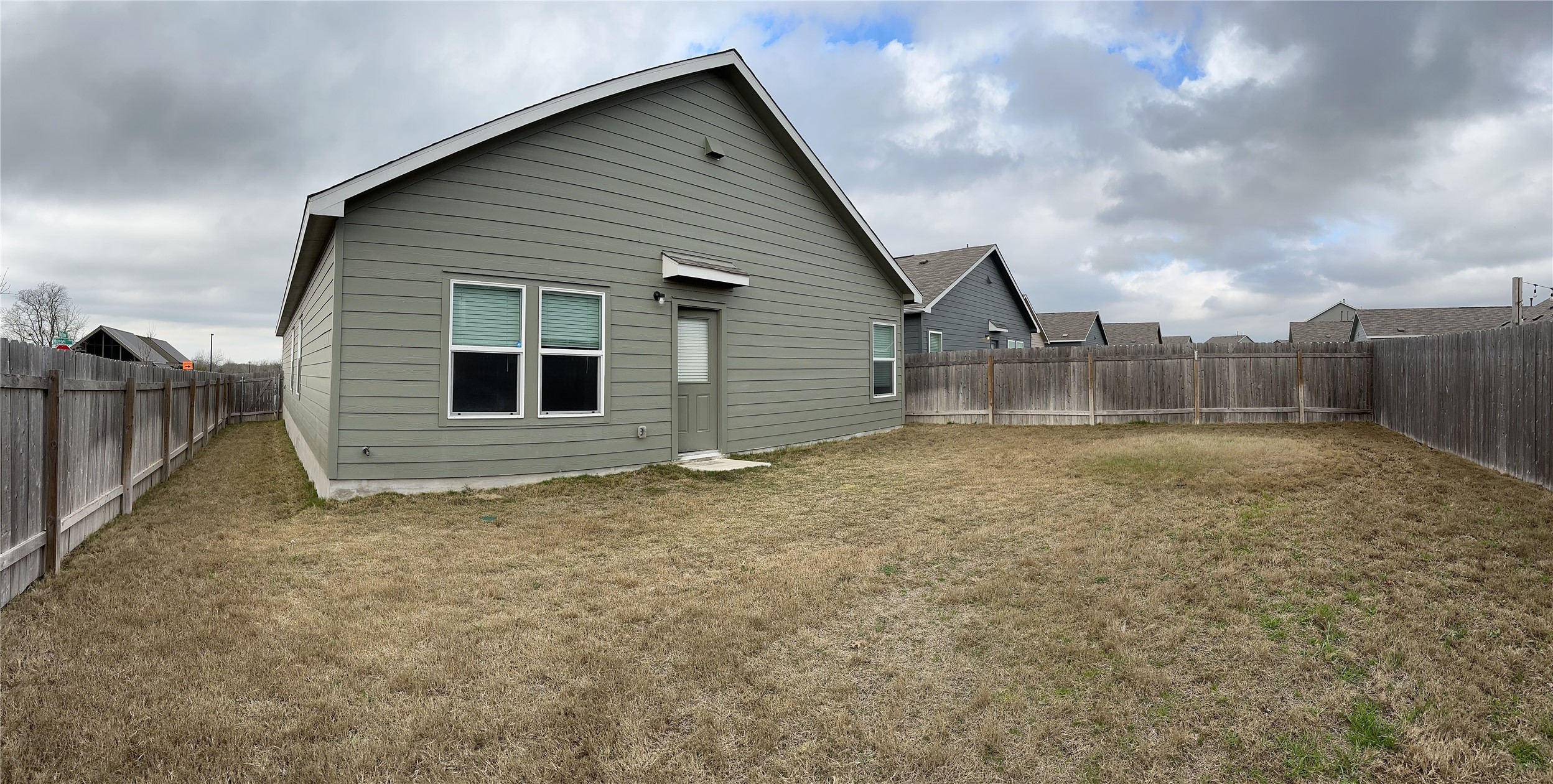 13501 Mussel Run Elgin, TX 78621 - Photo 16 of 28 Expansive fenced backyard with a single-story residence featuring horizontal siding and a side entry door
