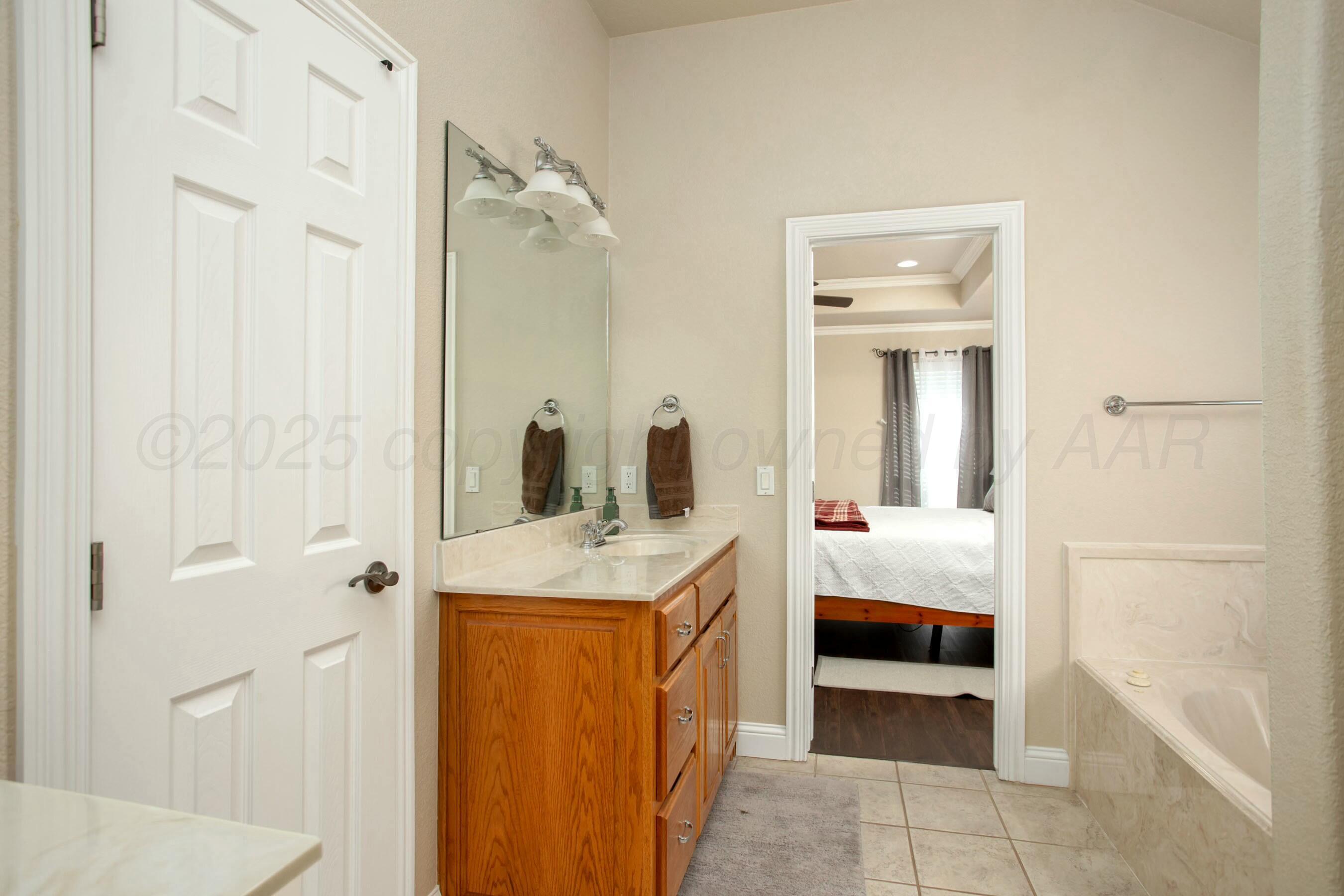 8103 El Paso Drive Amarillo, TX 79118 - Photo 17 of 40 a en suite bathroom with a double vanity sink a mirror and a bathtub
