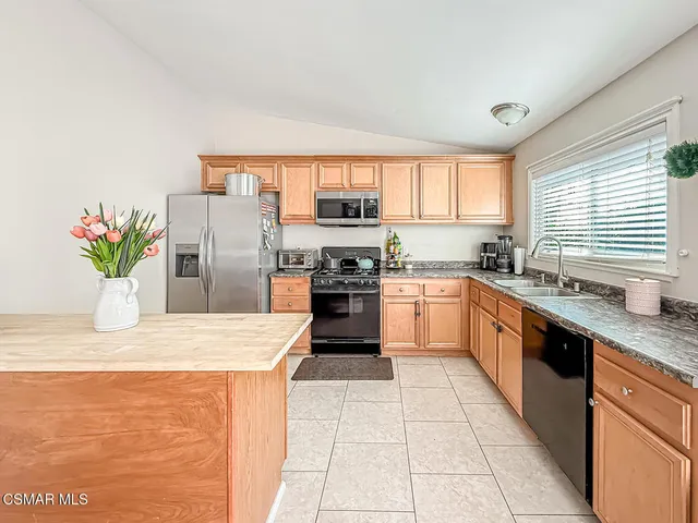 a kitchen with stainless steel appliances granite countertop a stove a sink and a refrigerator