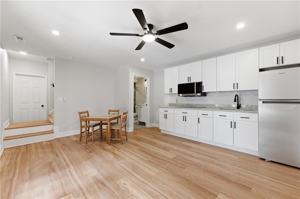 3571 Midvale Forest Court Tucker, GA 30084 - Photo 40 of 53 a kitchen with stainless steel appliances granite countertop a refrigerator a stove a microwave oven a dining table and chairs with wooden floor
