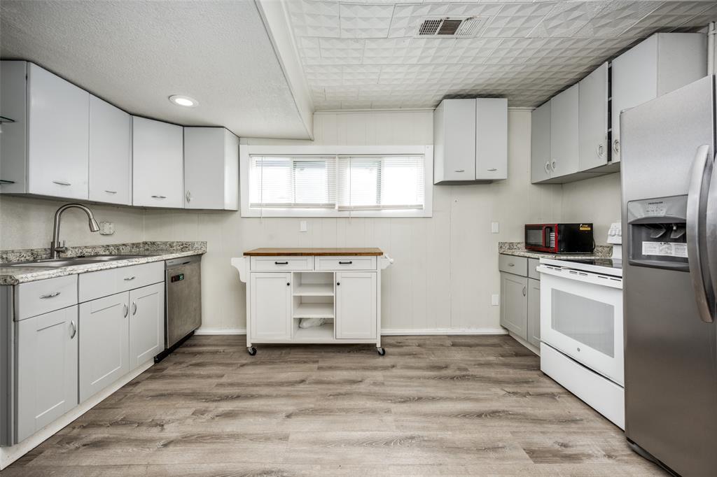 701 Lakey Street Denton, TX 76205 - Photo 11 of 25 a kitchen with granite countertop a stove a sink and white cabinets