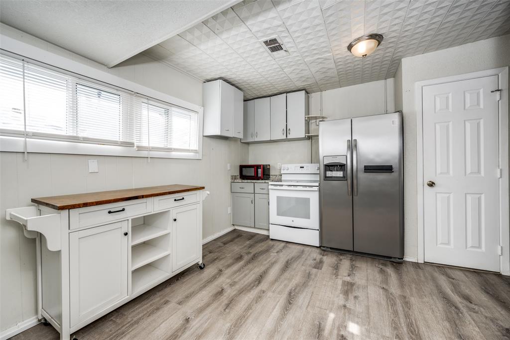 701 Lakey Street Denton, TX 76205 - Photo 12 of 25 a kitchen with white cabinets and stainless steel appliances