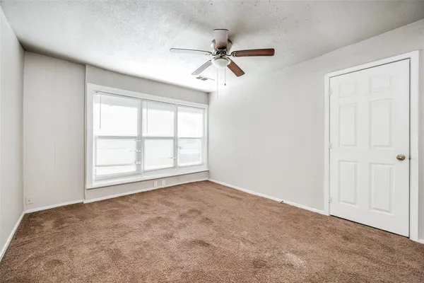 an empty room with windows and fan