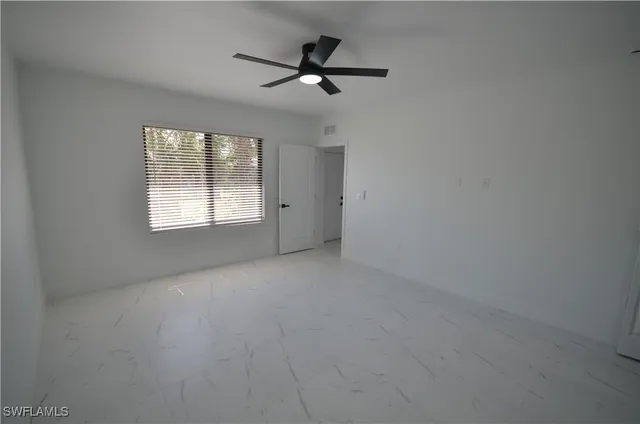 an empty room with a ceiling fan and window