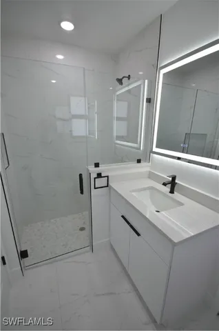 a bathroom with a sink a toilet a mirror and shower