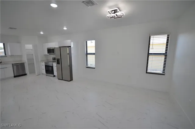 an empty room with a windows and a chandelier