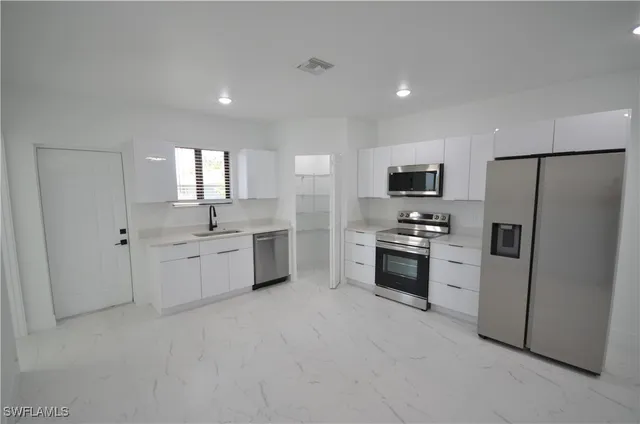 a kitchen with white cabinets and stainless steel appliances