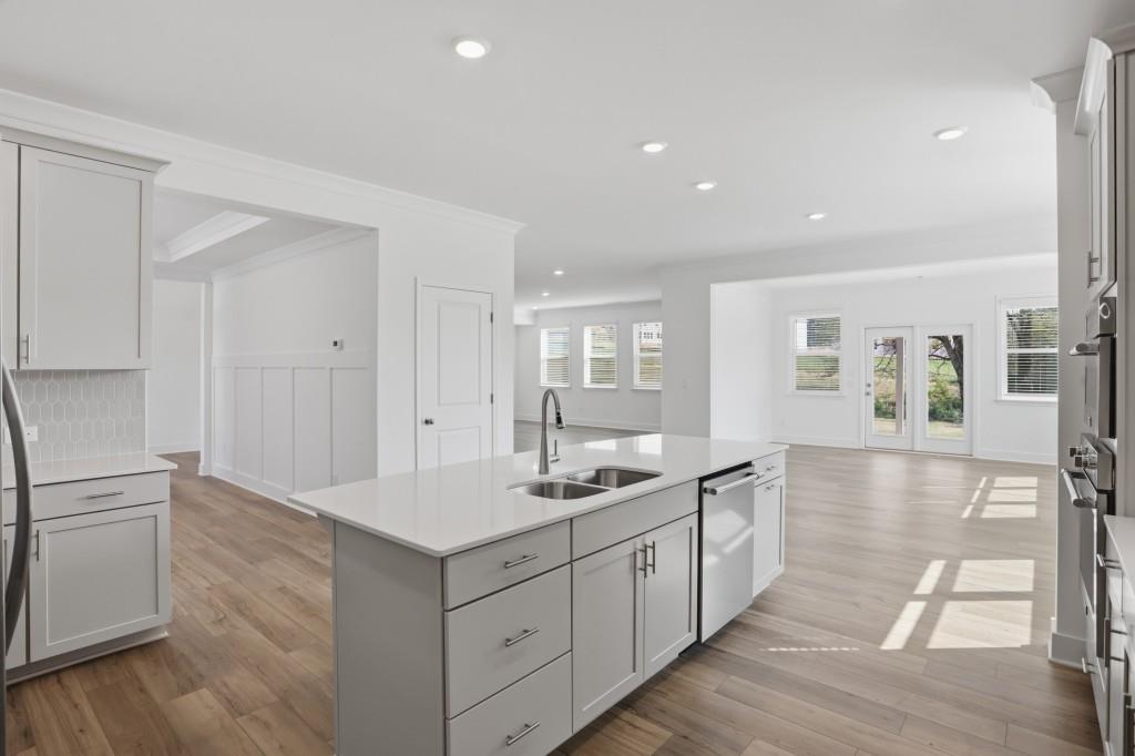 293 Deer Valley Run Canton, GA 30115 - Photo 7 of 8 a hall with kitchen island white cabinets and wooden floor