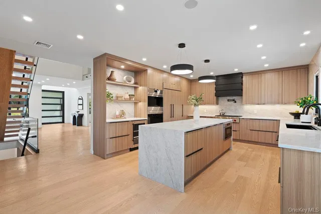 a large kitchen with stainless steel appliances granite countertop a large counter top a sink a stove a refrigerator and a cabinets