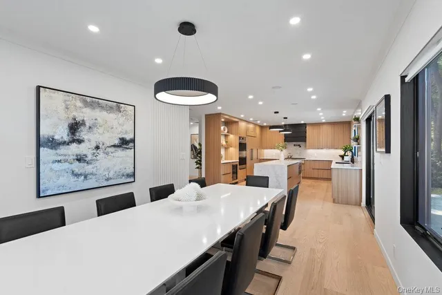 a large kitchen with kitchen island a refrigerator a stove a sink a dining table and chairs with wooden floor