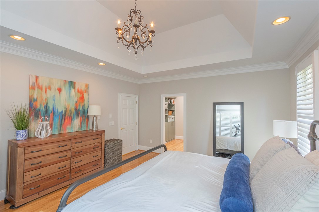 1104 Harpers Way Anderson, SC 29621 - Photo 17 of 50 This primary bedroom offers warm wood flooring and a beautiful tray ceiling with an elegant chandelier.