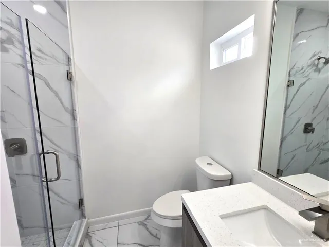 a white toilet sitting next to a bathroom sink and a shower