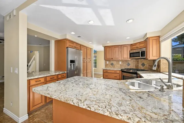 a kitchen with stainless steel appliances granite countertop a sink refrigerator and microwave