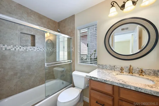 a bathroom with a granite countertop toilet a sink and a mirror