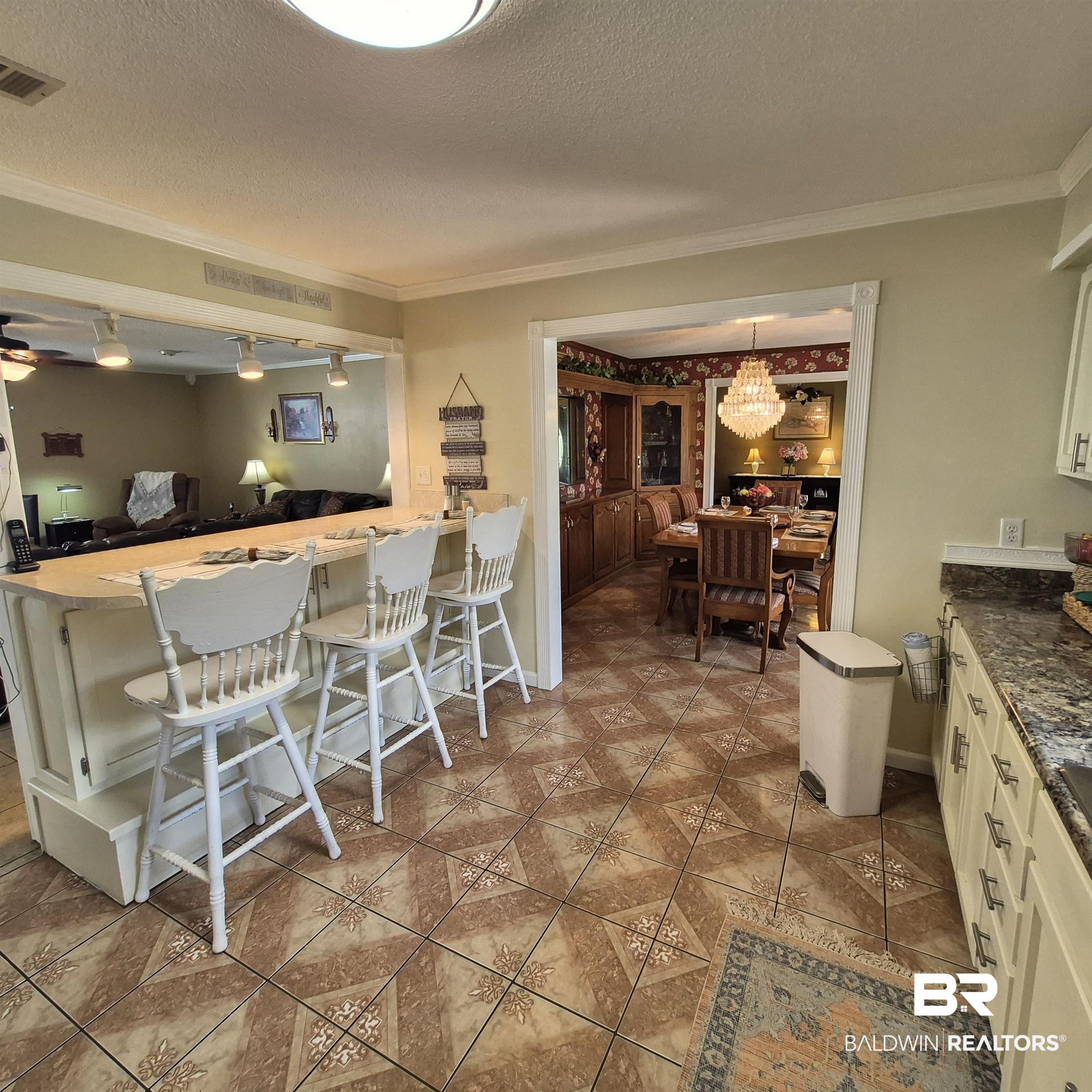 26635 Highway 41 Range, AL 36473 - Photo 16 of 74 Kitchen with a textured ceiling, a kitchen bar, crown molding, white cabinetry, and dark stone countertops
