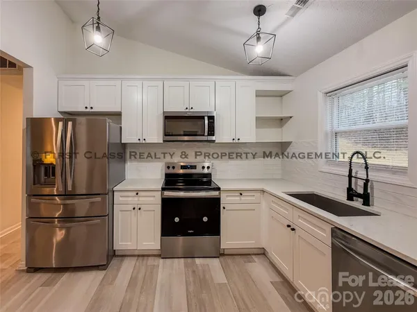 a kitchen with granite countertop a refrigerator a sink dishwasher a stove and a refrigerator with wooden floor