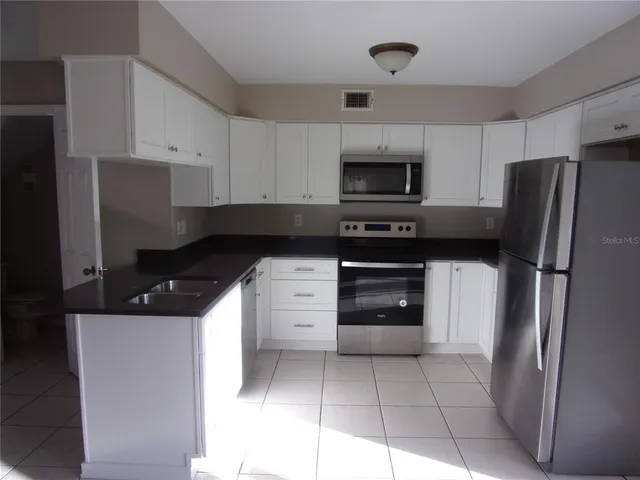 a kitchen with stainless steel appliances granite countertop a refrigerator and a stove