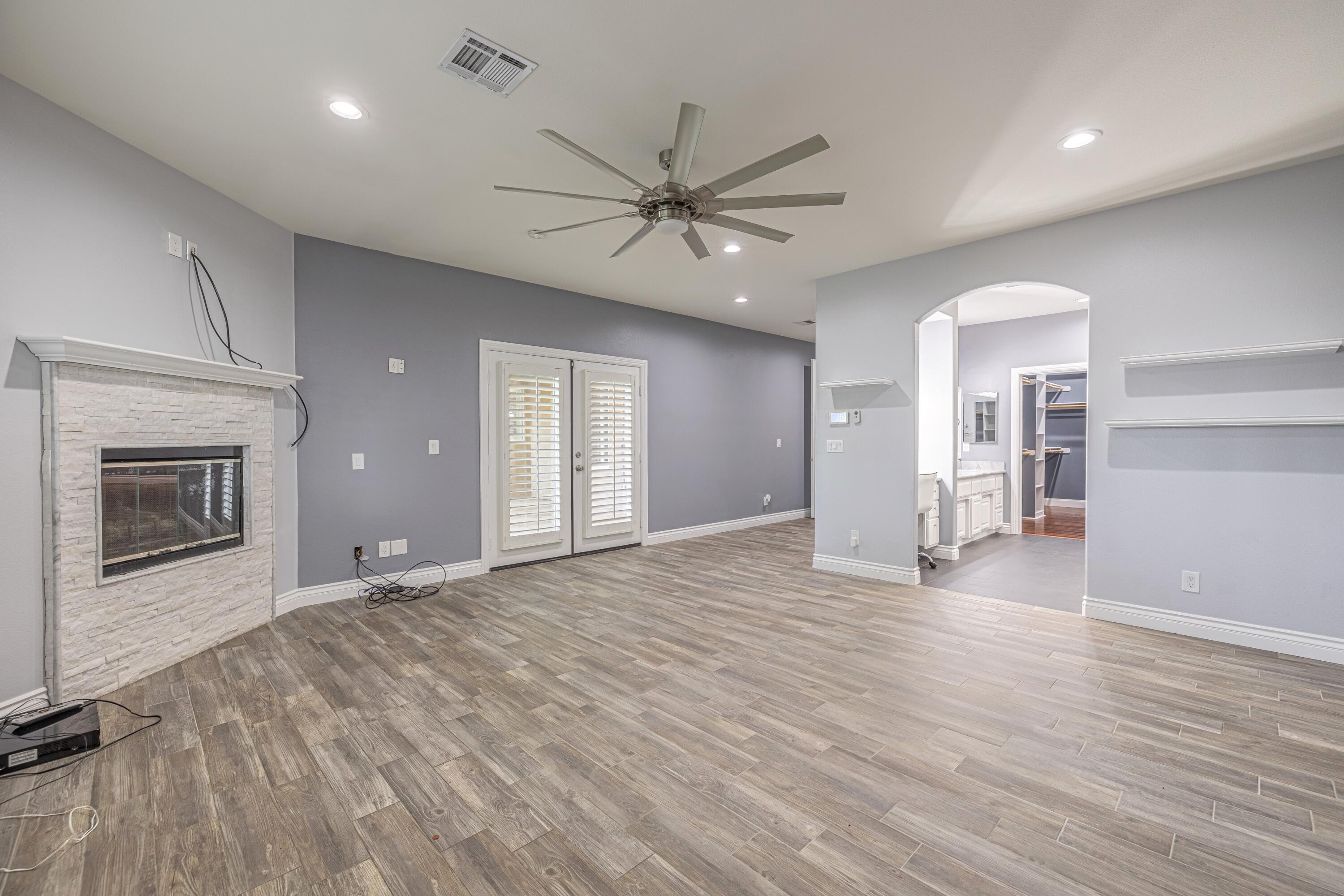 4023 Derby Circle Lancaster, CA 93536 - Photo 16 of 53 an empty room with wooden floor a ceiling fan a fireplace and windows